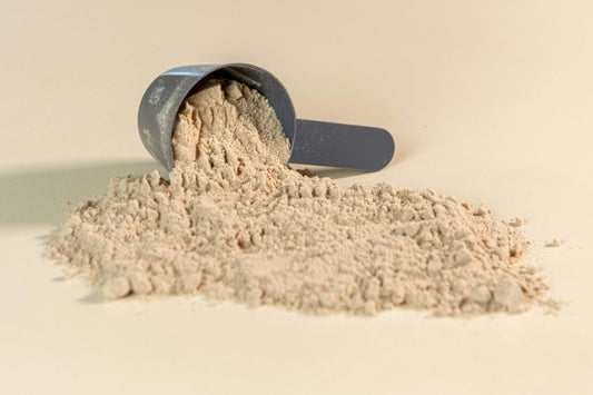 Scoop of whey protein powder spilled on a surface, highlighting its texture and nutritional value.